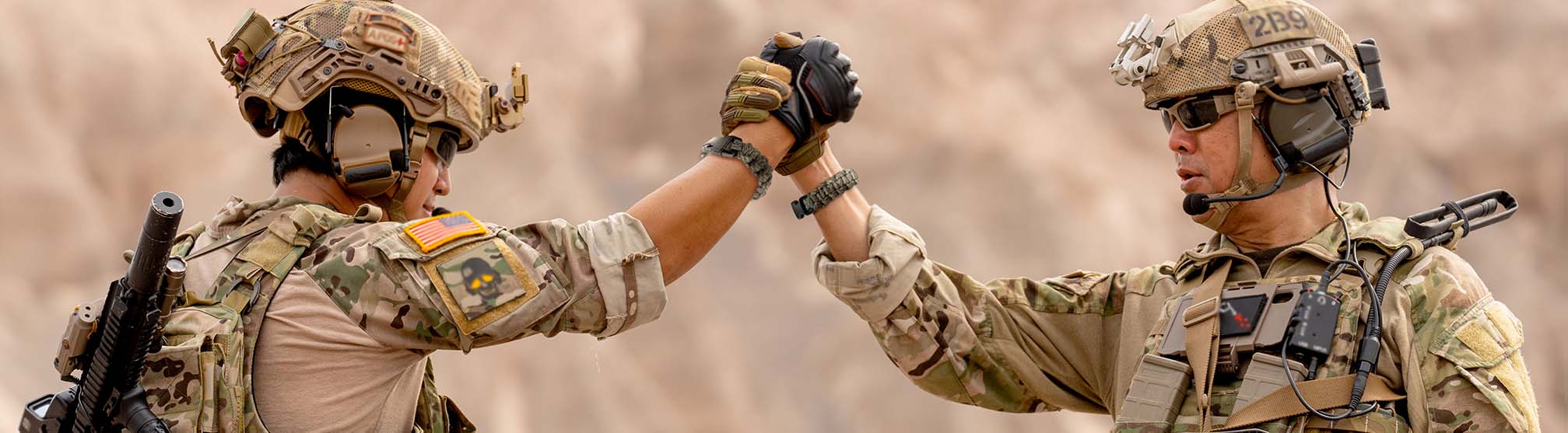 Two soldiers in uniform shaking hands, wearing paracords bracelets.